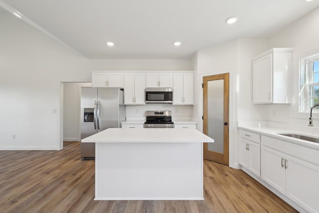 kitchen featuring light wood-style floors, light countertops, stainless steel appliances, white cabinetry, and a kitchen island