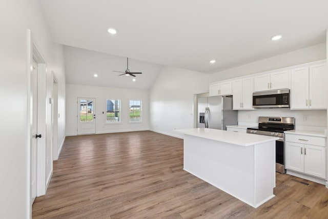 kitchen with stainless steel appliances, ceiling fan, vaulted ceiling, and white cabinetry