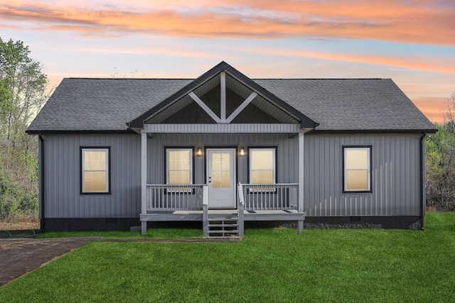 view of front facade featuring a porch, a shingled roof, a front lawn, and crawl space