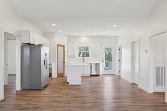 kitchen featuring visible vents, wood finished floors, light countertops, stainless steel appliances, and white cabinetry