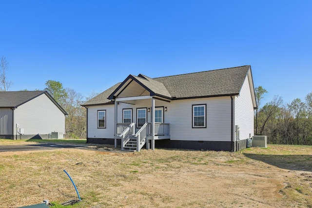 view of front of home with a shingled roof, crawl space, and cooling unit