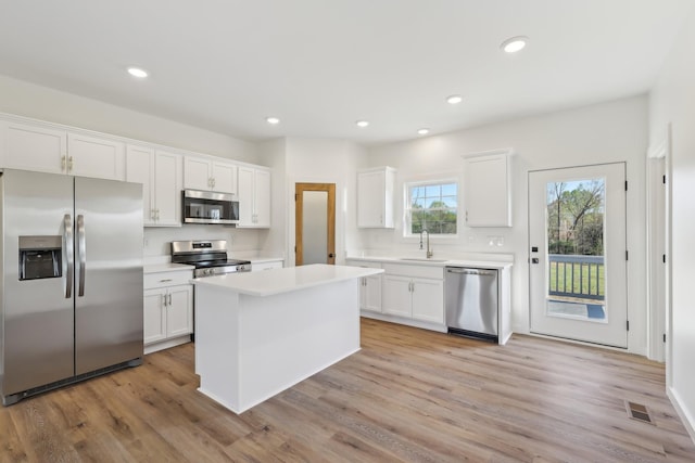 kitchen featuring light countertops, white cabinets, a sink, light wood-style flooring, and stainless steel appliances
