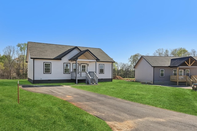 view of front of house with roof with shingles, a front lawn, and crawl space
