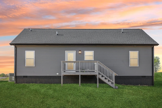 back of property at dusk with a yard and crawl space