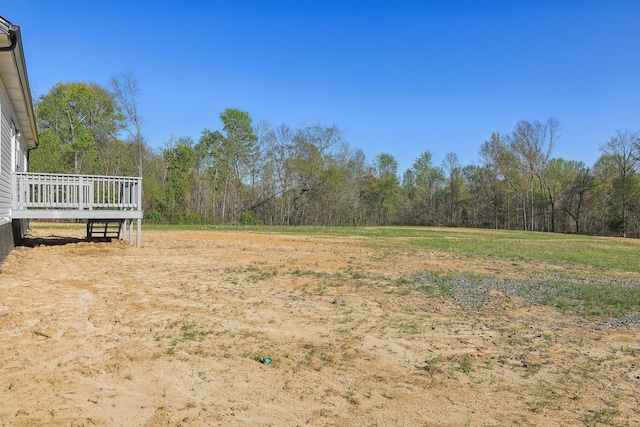 view of yard with a forest view and a wooden deck