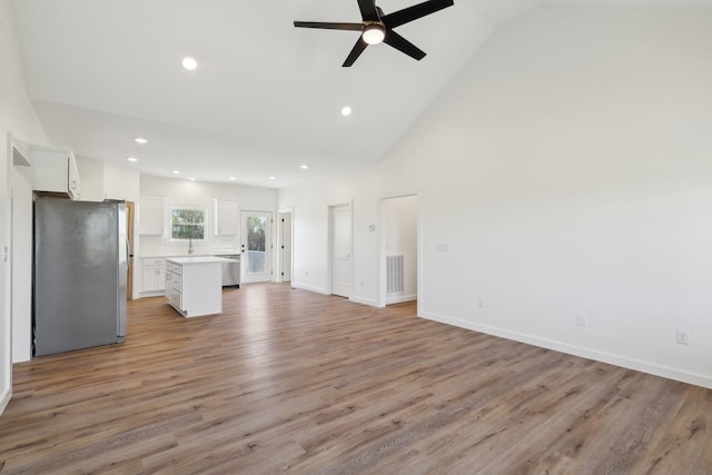 unfurnished living room with ceiling fan, light wood finished floors, high vaulted ceiling, recessed lighting, and baseboards