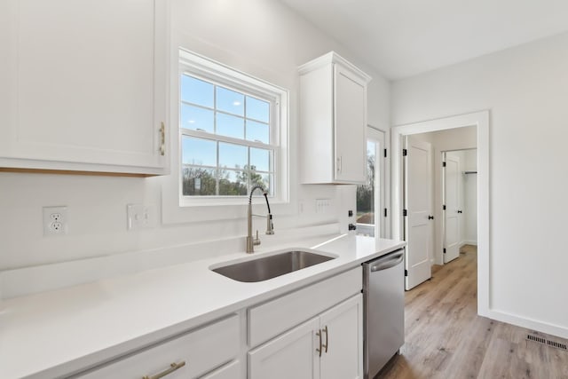 kitchen featuring visible vents, dishwasher, a sink, light countertops, and white cabinets