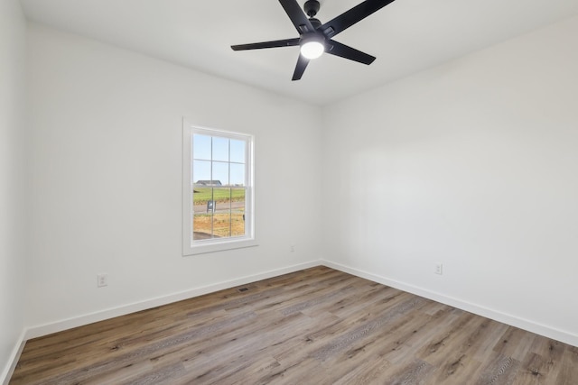 unfurnished room featuring a ceiling fan, baseboards, visible vents, and wood finished floors