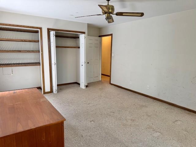 unfurnished bedroom featuring multiple closets, carpet, and baseboards