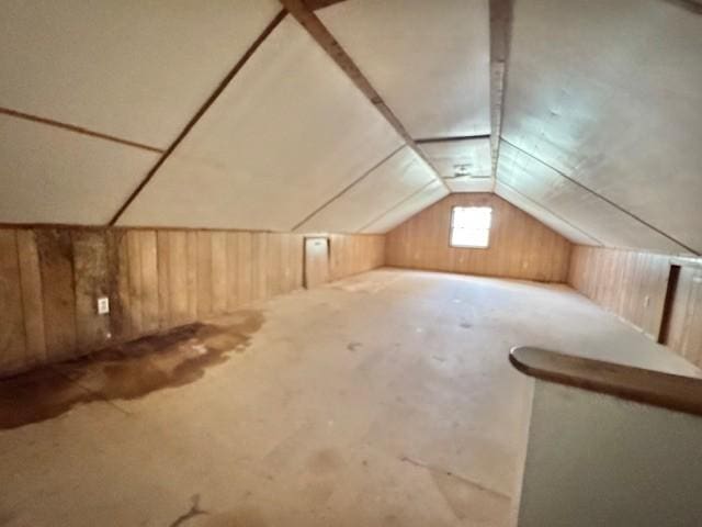 bonus room with wooden walls and lofted ceiling