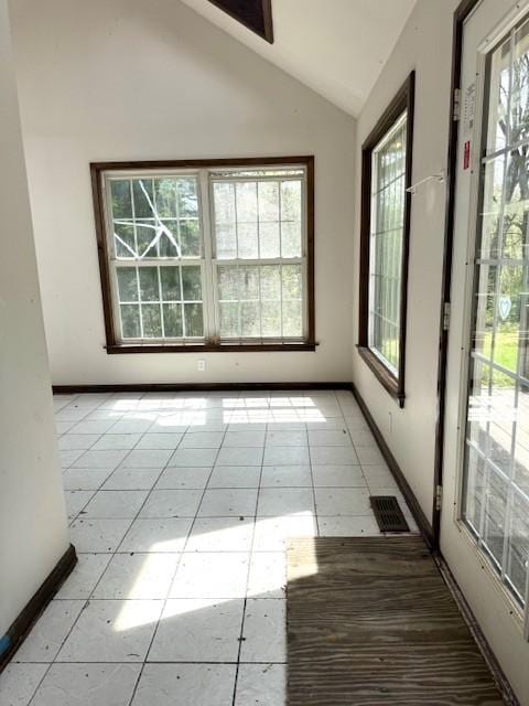 spare room with light tile patterned floors, visible vents, baseboards, and lofted ceiling