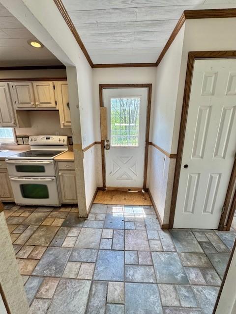 kitchen featuring double oven range, ornamental molding, light countertops, stone tile floors, and light brown cabinetry