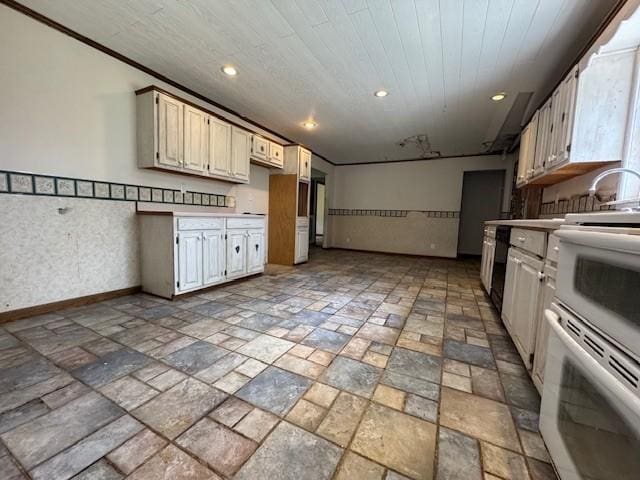 kitchen with baseboards, stone tile flooring, light countertops, recessed lighting, and stove