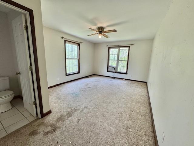 carpeted spare room with tile patterned floors, ceiling fan, and baseboards
