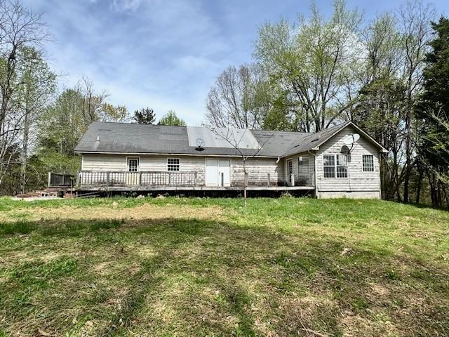 rear view of house with a yard and a wooden deck