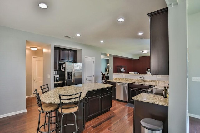 kitchen with stainless steel appliances, dark wood-type flooring, backsplash, and light stone counters