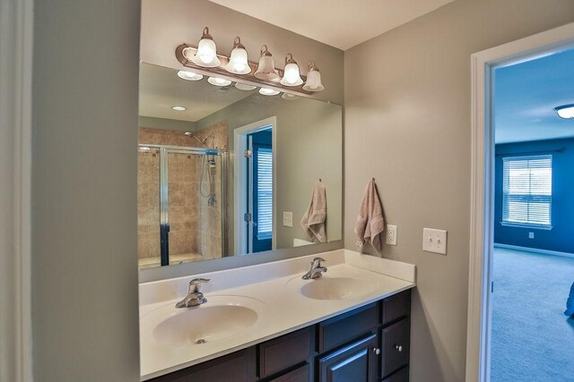 bathroom featuring a shower stall, double vanity, and a sink