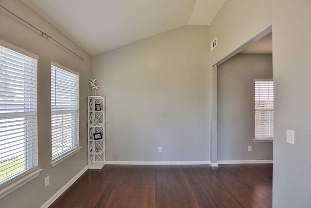 unfurnished room with dark wood-type flooring, visible vents, baseboards, and lofted ceiling