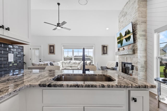 kitchen with stone counters, open floor plan, a stone fireplace, and plenty of natural light