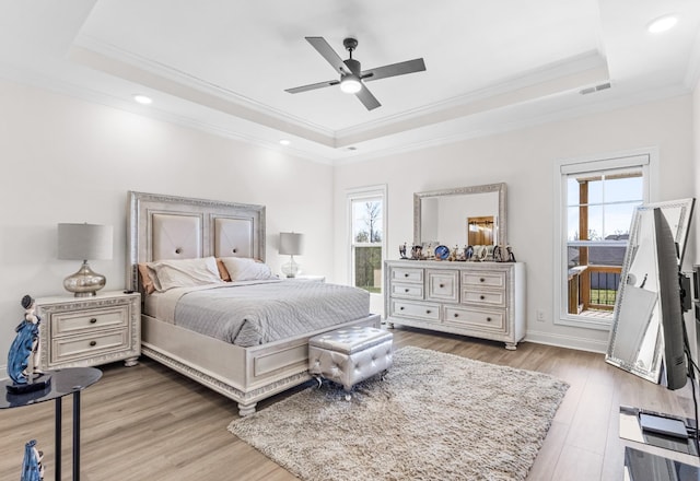 bedroom with visible vents, wood finished floors, ornamental molding, and a raised ceiling