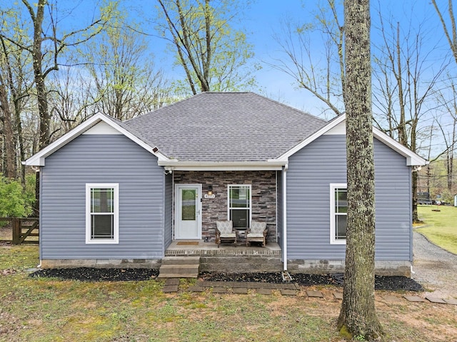 view of front facade with a shingled roof and a front yard