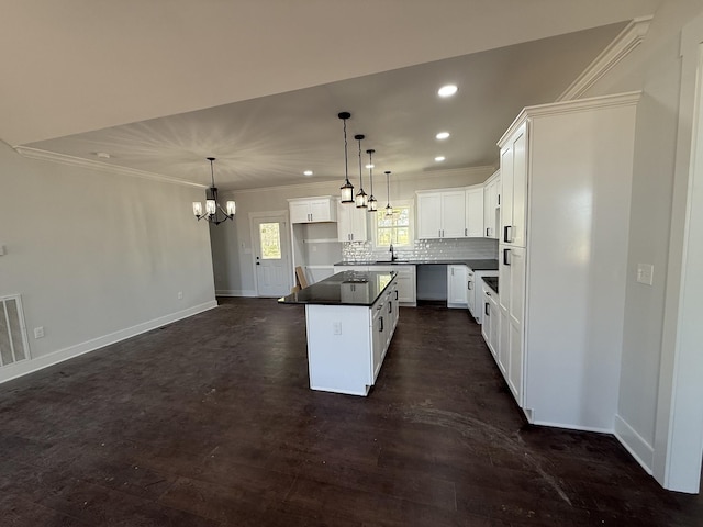 kitchen with crown molding, an inviting chandelier, recessed lighting, a kitchen island, and decorative backsplash