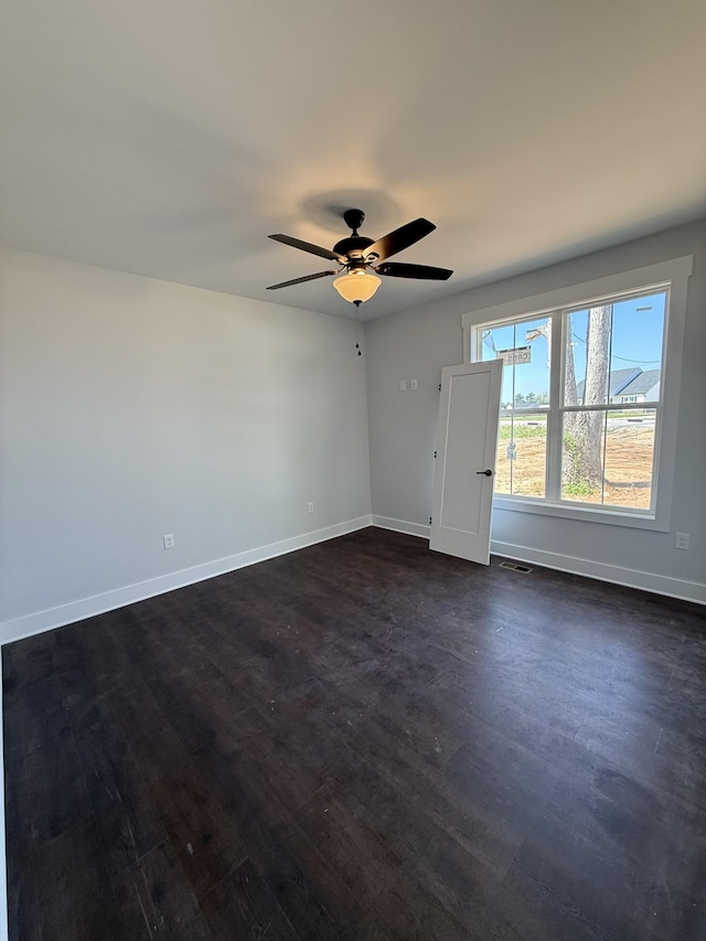 spare room featuring dark wood-style flooring, baseboards, a ceiling fan, and visible vents