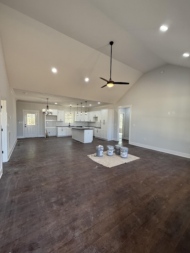 unfurnished living room featuring ceiling fan with notable chandelier, baseboards, and a healthy amount of sunlight