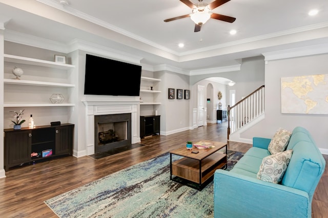 living room featuring arched walkways, a fireplace with flush hearth, wood finished floors, and ceiling fan
