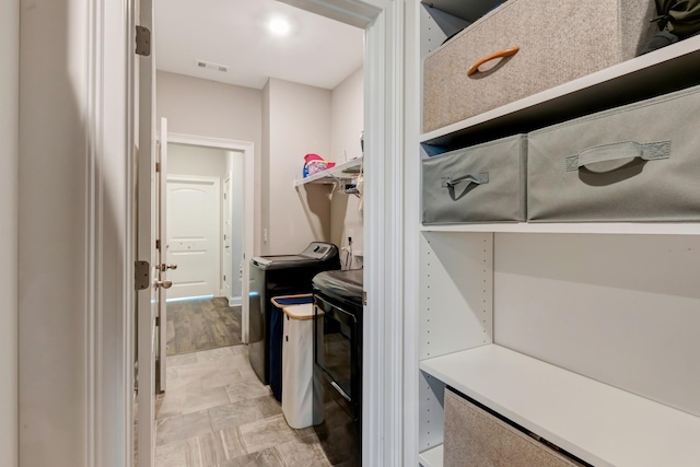 clothes washing area with visible vents, laundry area, and washing machine and clothes dryer