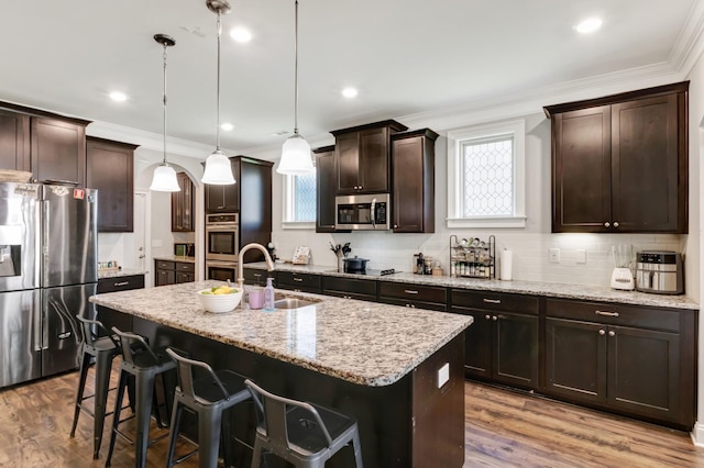 kitchen featuring a center island with sink, appliances with stainless steel finishes, a sink, and ornamental molding