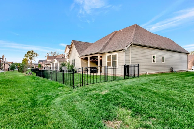 view of side of property featuring a shingled roof, fence, and a lawn