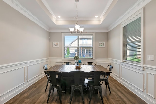 dining area featuring an inviting chandelier, dark wood-type flooring, wainscoting, a raised ceiling, and a decorative wall