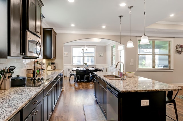 kitchen with arched walkways, appliances with stainless steel finishes, a sink, and a wealth of natural light