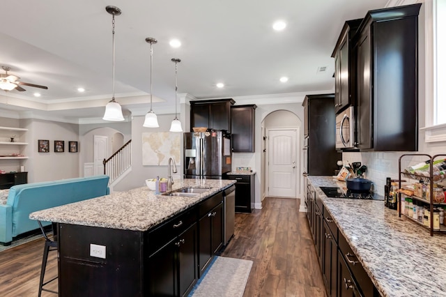 kitchen with appliances with stainless steel finishes, open floor plan, ceiling fan, arched walkways, and a sink