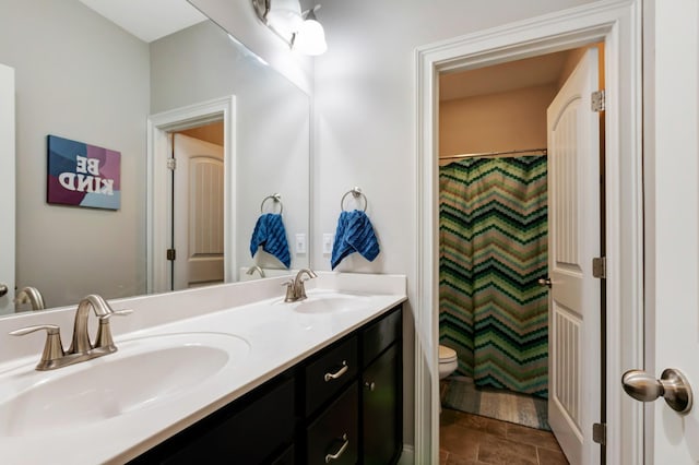 bathroom with toilet, double vanity, and a sink