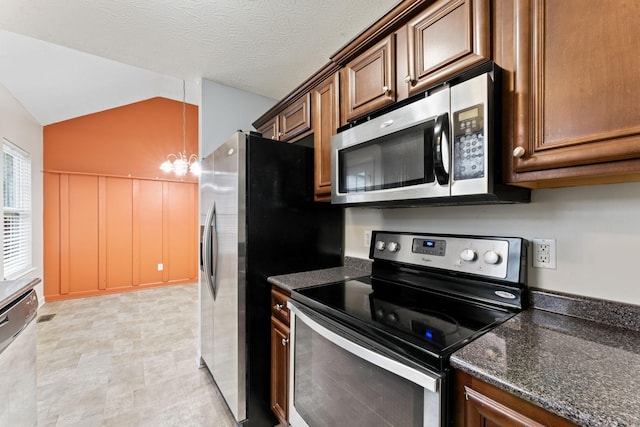kitchen featuring appliances with stainless steel finishes, dark stone counters, vaulted ceiling, and a textured ceiling