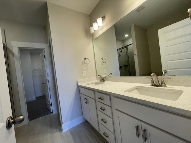 bathroom featuring a shower stall, wood finished floors, a sink, and visible vents