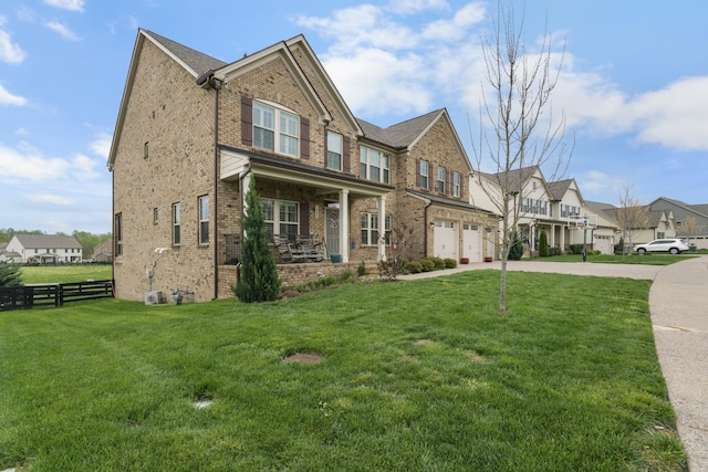 craftsman-style house with a front yard, fence, brick siding, an attached garage, and a residential view