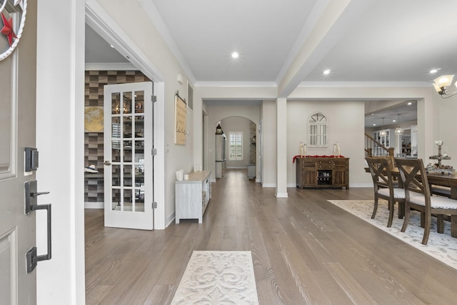 foyer entrance featuring crown molding, arched walkways, recessed lighting, wood finished floors, and baseboards