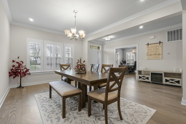 dining area with light wood-type flooring, an inviting chandelier, ornamental molding, recessed lighting, and visible vents