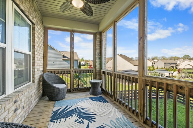 sunroom / solarium featuring a ceiling fan and a residential view