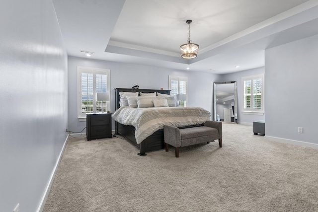 bedroom featuring a tray ceiling, light colored carpet, baseboards, and a notable chandelier