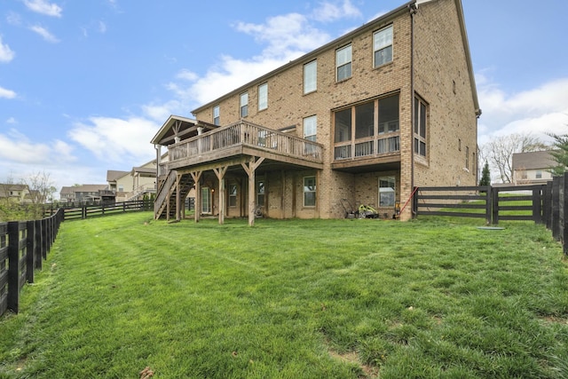 rear view of property with brick siding, a fenced backyard, and a lawn