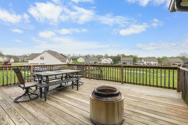 wooden deck with outdoor dining area, a residential view, and a lawn