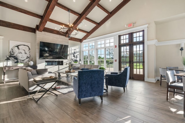 living area with wood finished floors, high vaulted ceiling, beamed ceiling, and a notable chandelier