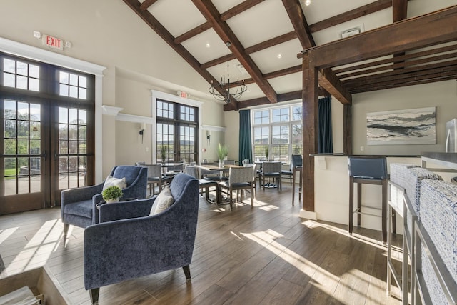 living room featuring an inviting chandelier, a high ceiling, beam ceiling, wood finished floors, and french doors