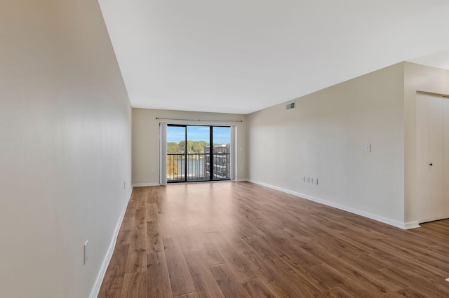 spare room featuring visible vents, baseboards, and wood finished floors
