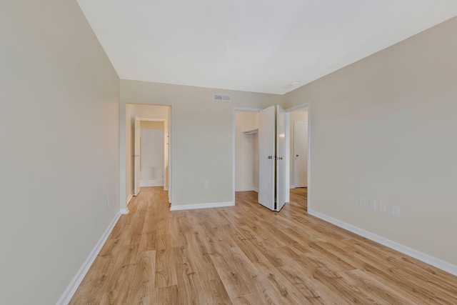 empty room with visible vents, light wood-type flooring, and baseboards
