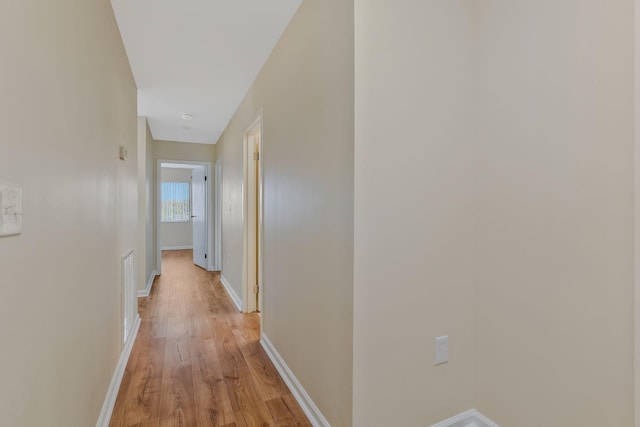 corridor with visible vents, baseboards, and light wood-type flooring